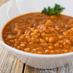 A view of a bowl of farro bean soup, in a restaurant or kitchen setting.